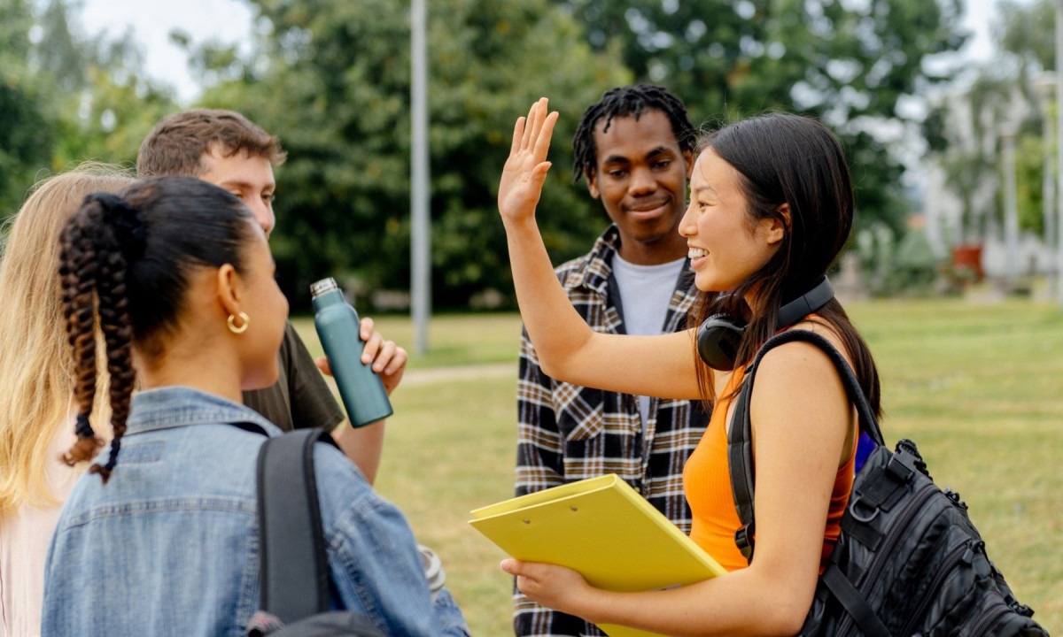  asian student high-fives her classmates upon arriving at the college or university campus. Back to school after summer vacation
     -  (crédito:  Getty Images)