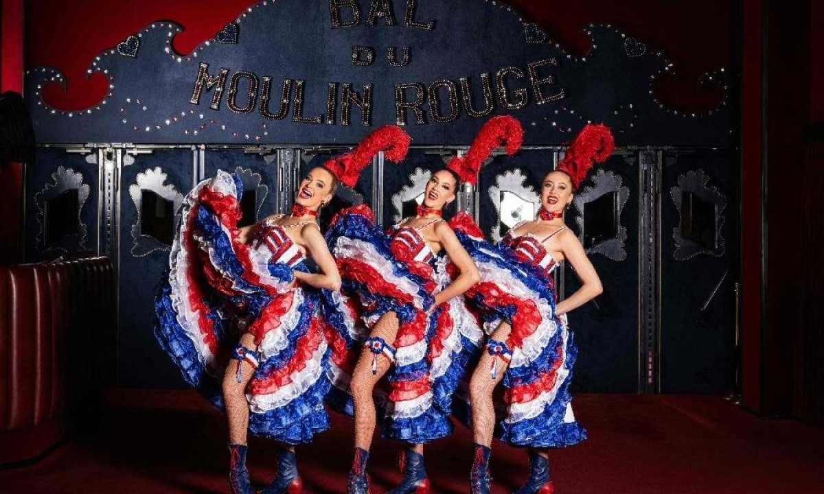 As dan&ccedil;arinas do Moulin Rouge, Fanny, Keira e Alana, vestindo trajes franceses Cancan feitos de an&aacute;gua, calcinha e espartilho, liga e botins, posam na entrada do cabar&eacute; &quot;Le Moulin Rouge&quot; em Paris   -  (crédito: MIGUEL MEDINA/AFP)