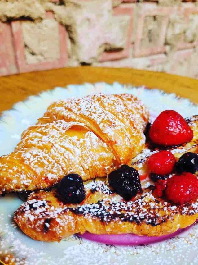 Croissant French Toast embebida em creme baunilhado acompanhada de frutas e xarope de bordo Croissant French Toast embebida em creme baunilhado acompanhada de frutas e xarope de bordo