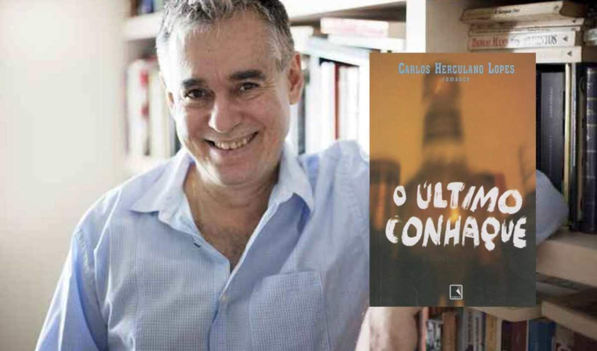 Homem grisalho ao lada de uma prateleira de livros.