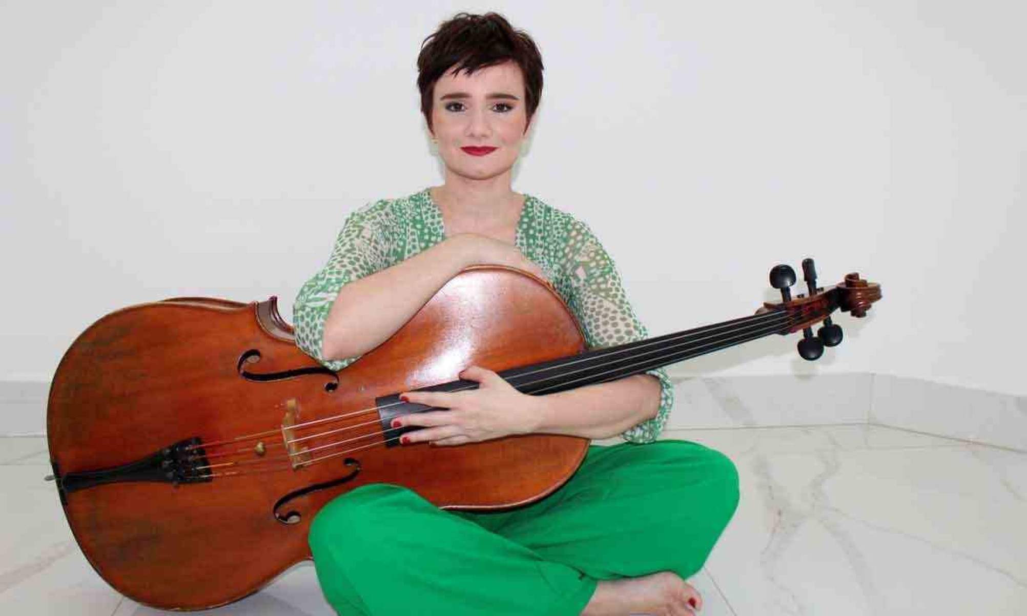 violoncelista Carolina Rodrigues está segurando um violoncelo 