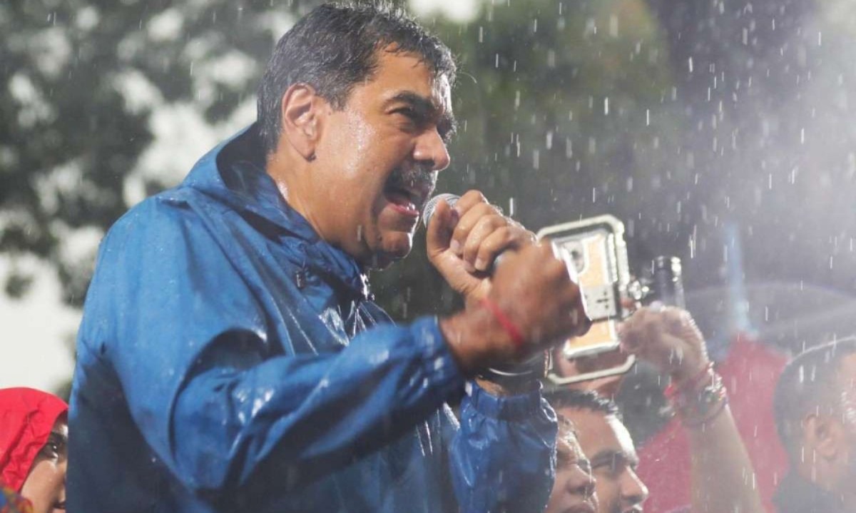 Sob chuva, Nicolás Maduro pede boicote ao whatsapp, ferramenta pela qual, diz o ditador venezuelano, apoiadores dele receberam ameaças -  (crédito: MARCELO GARCIA / Miraflores press office / AFP)