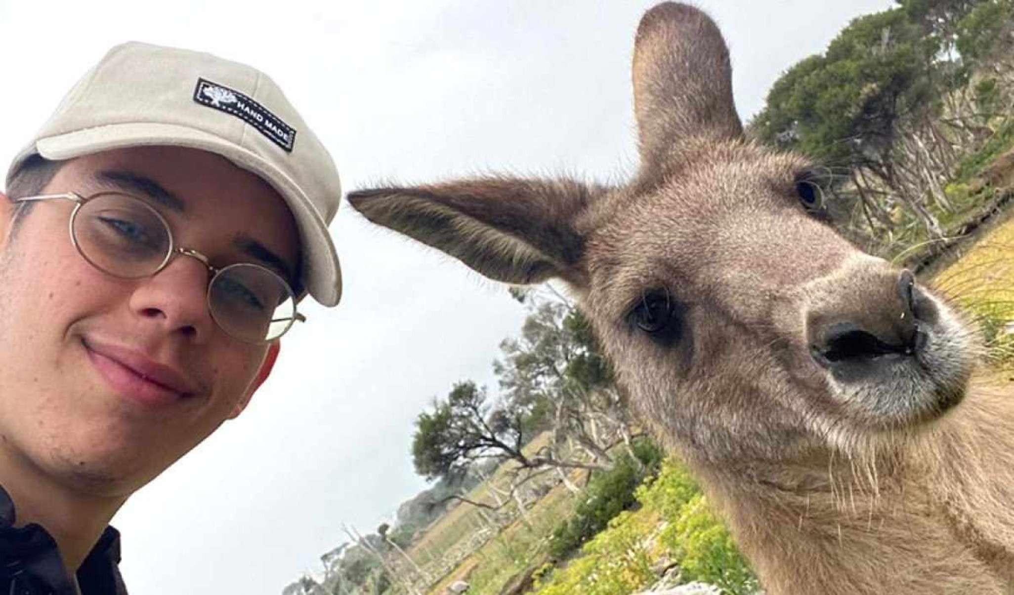 Jovem na Austrália ao lado de um canguru.