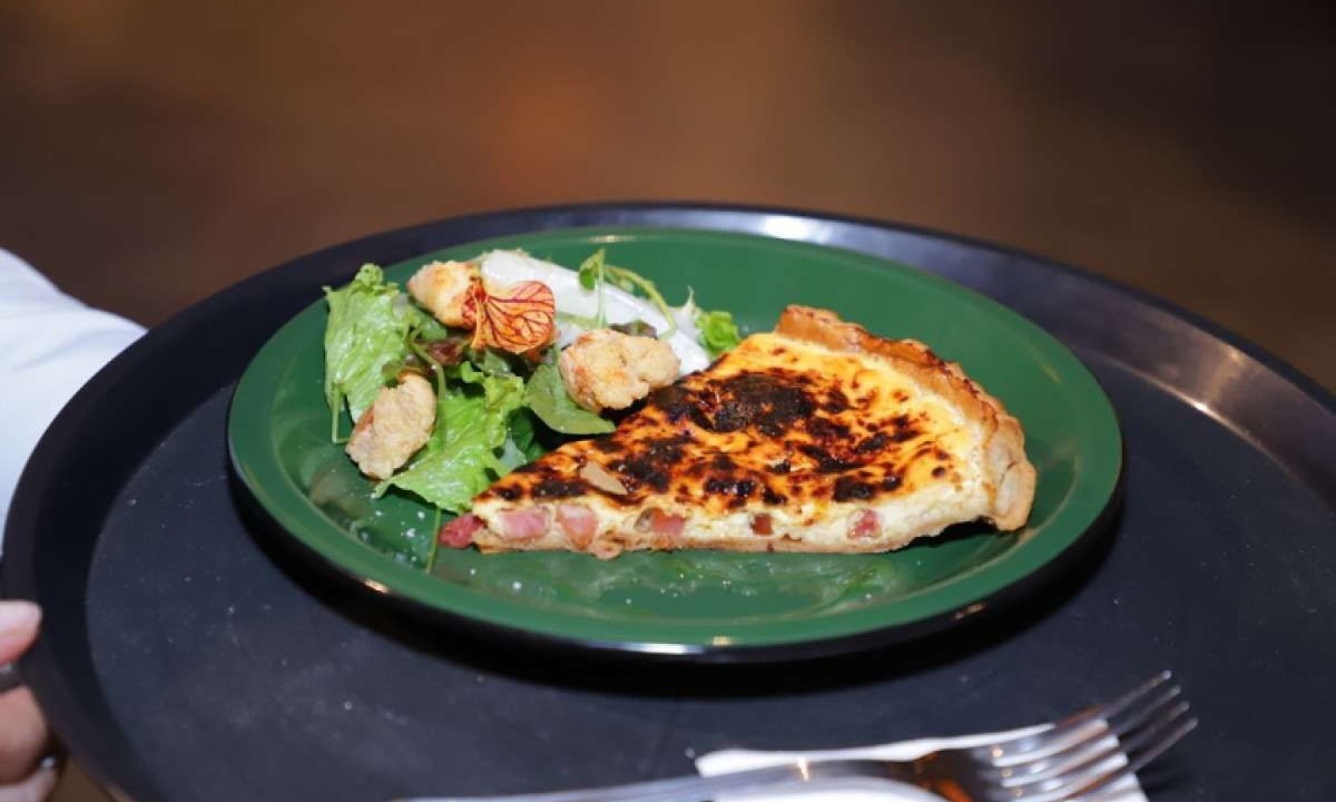 Feita pelos alunos do Inhac, a Lorraine, tradicional quiche francesa feita com queijo e bacon, servida com salada, croutons de pão de queijo e azeite defumado, será servida no Café-escola