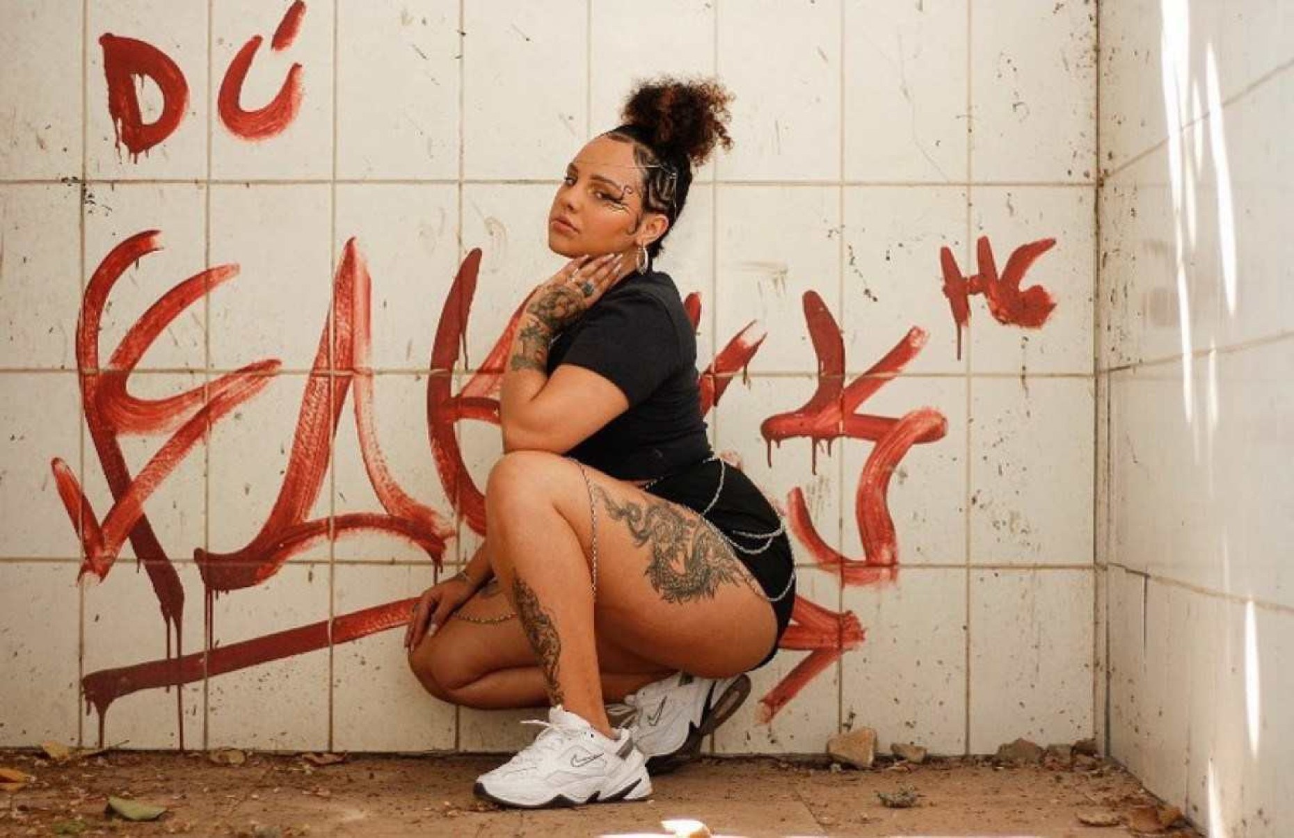 A rapper Laura Sette está agachada e olha para a câmera