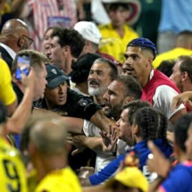  Colombia's supporters (L) clash with Uruguay's supporters, alongside Uruguay's defender #04 Ronald Araujo (R), at the end of the Conmebol 2024 Copa America tournament semi-final football match between Uruguay and Colombia at Bank of America Stadium, in Charlotte, North Caroline on July 10, 2024. (Photo by JUAN MABROMATA / AFP)
     -  (crédito:  AFP via Getty Images)