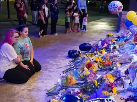 Duas meninas sentam-se em frente a um memorial depois que membros da comunidade, alunos e professores da Apalachee High School se reuniram para uma vigília em Monroe, Geórgia -  (crédito: MEGAN VARNER/Getty Images via AFP)