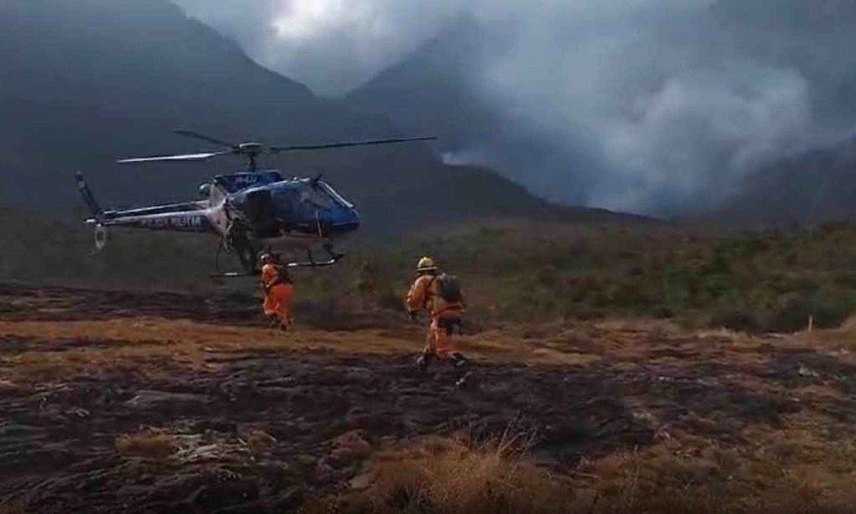 Bombeiros se aproximam de helicóptero da Polícia Militar em meio ao combate a incêndios florestais no Caraça -  (crédito: Reprodução/CBMMG)