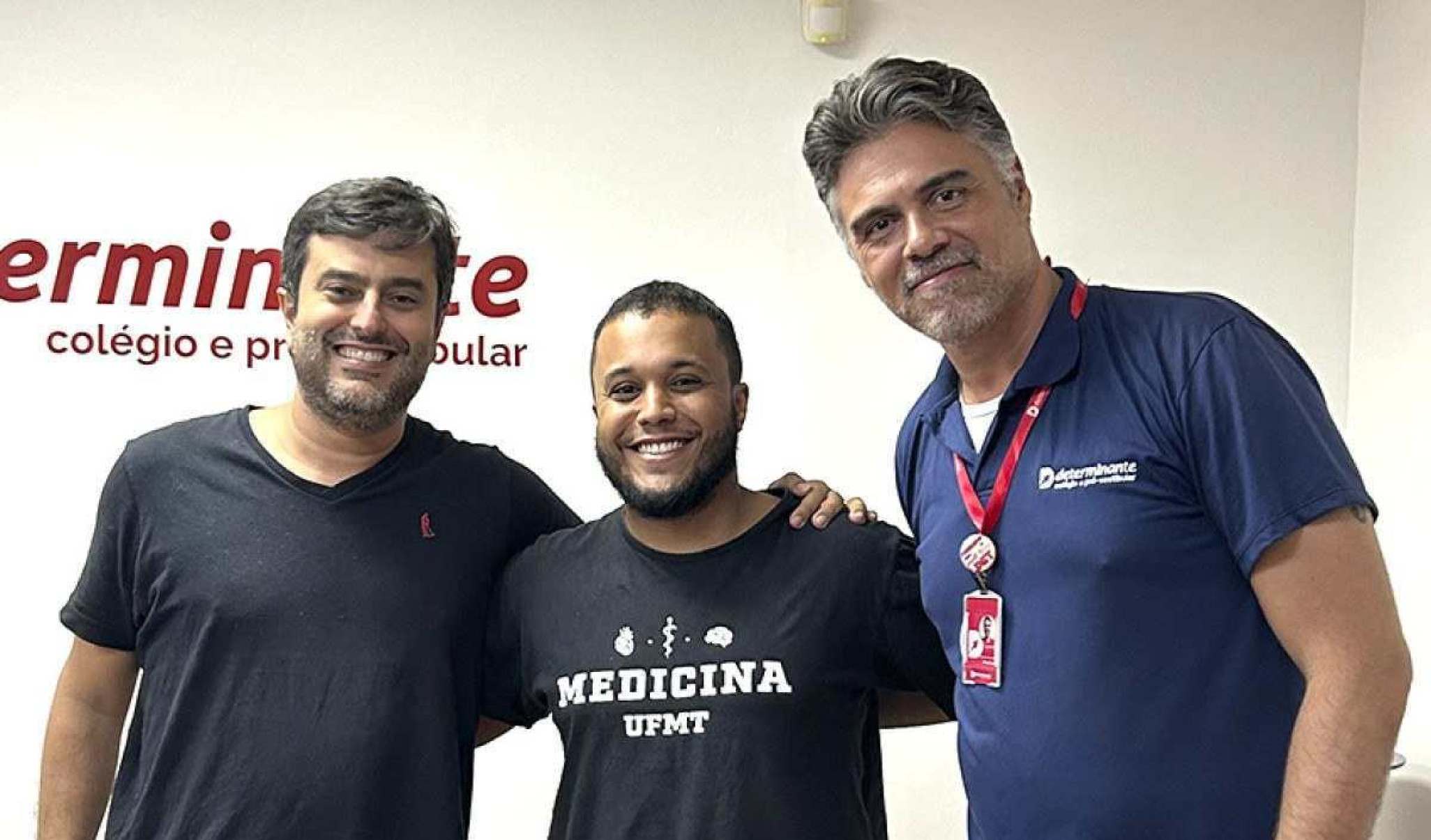 Aluno jovem entre dois adultos com a camisa de Medicina da Universidade Federal do Mato Grosso