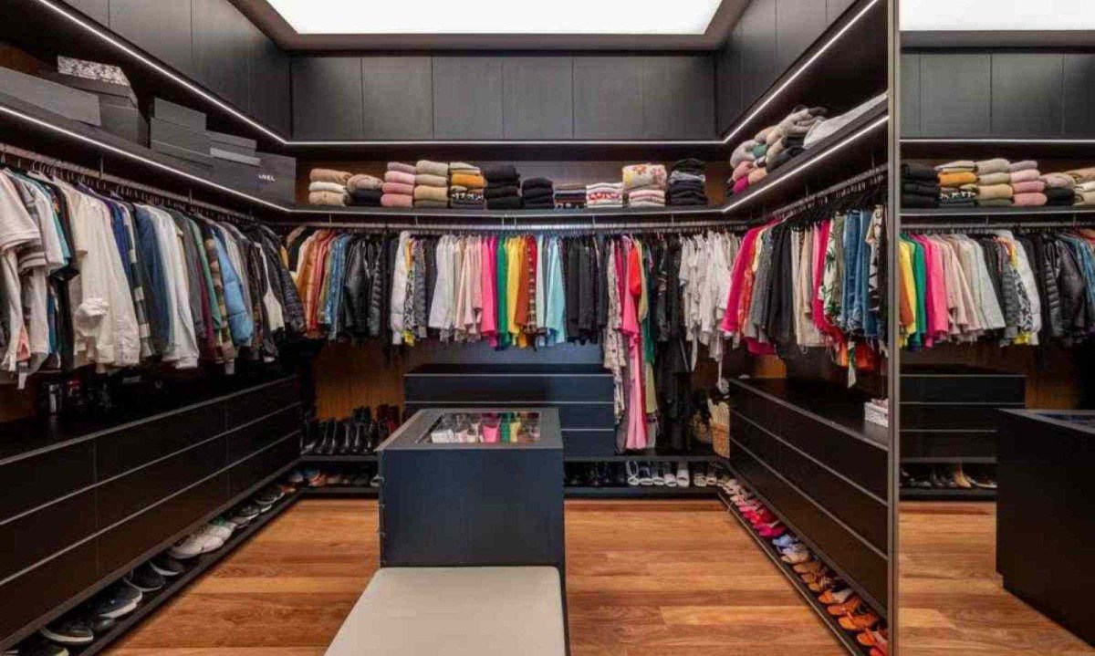 O closet do casal bem espaçoso apresentando uma ilha de acessórios