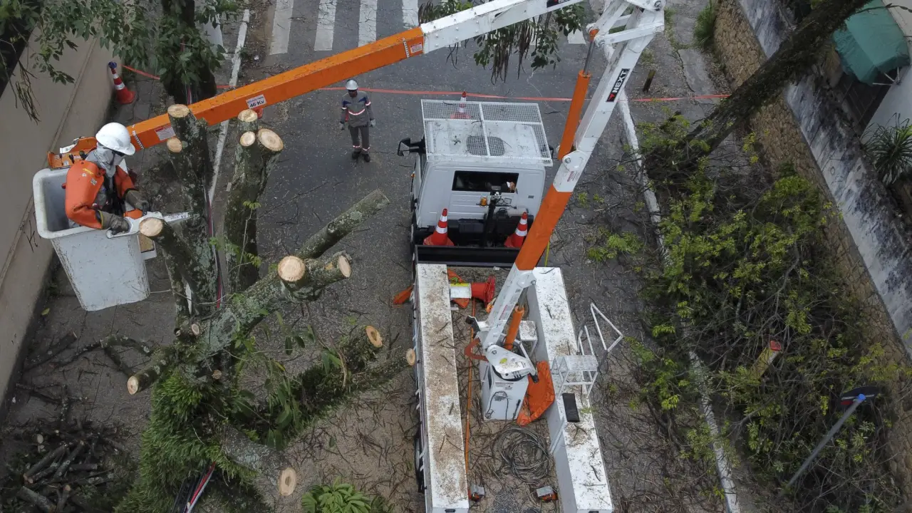 Chuvas em São  Paulo derrubam árvóres e provocam queda de energia,  deixando milhares  sem luz há mais de uma semana -  (crédito: MIGUEL SCHINCARIOL/AFP)   Leia mais em: https://veja.abril.com.br/brasil/grande-sp-registra-93-mil-imoveis-sem-energia-apos-chuva-de-intensidade-moderada)