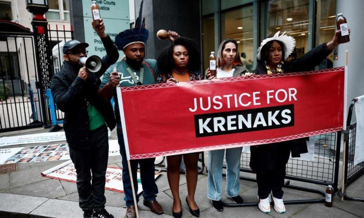  Indígena Wakrewa Krenak (direita), de Conselheiro Pena (MG), segura garrafa de água contaminada retirada do rio Doce, em frente ao Supremo Tribunal de Justiça de Londres, no dia da abertura do julgamento das responsabilidades da mineradora BHP pelo desastre de Mariana, em 2015 -  (crédito: BENJAMIN CREMEL / AFP)