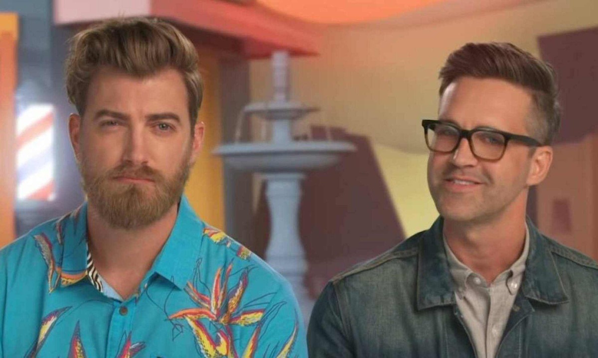 Rhett &Link. O homem da esquerda é branco e possui cabelo e baba médios e loiros. Ele usa uma blusa floral azul. O homem da direita também é branco e possui cabelo curto e preto, sua barba é grisalha. Ele usa uma jaqueta jeans. 