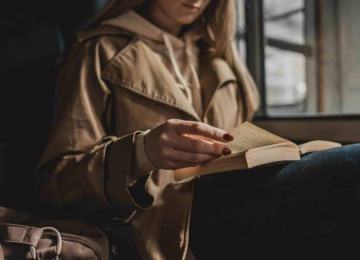 Mulher lê livro, sentada em sofá, ciente da importância da leitura para um melhor processo de cognição  -  (crédito: freepik)