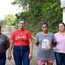 Daniela, Roseni, silvana e Ana paula diante da placa que consideram errada em rota de fuga, por estar voltada para a barragem. Mineradora afirma que posicionamento é correto