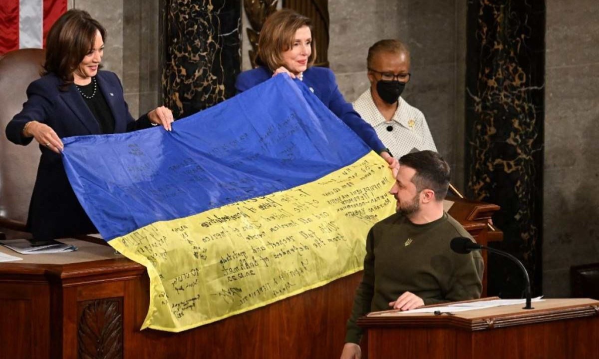 Presidente da Ucrânia, Volodymyr Zelensky, entrega uma bandeira nacional ucraniana à presidente da Câmara dos EUA, Nancy Pelosi (centro da foto) e à vice-presidente dos EUA, Kamala Harris, durante discurso em Washington, DC, em dezembro de 2022 -  (crédito: Jim WATSON / AFP)