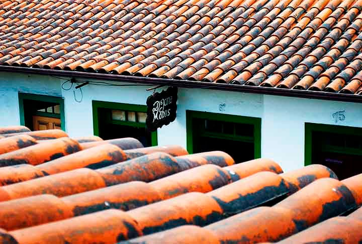 A “telha em duas águas” , comum na época, tem um estilo de cobertura ou telhado em que duas superfícies inclinadas se encontram em um ponto central mais alto, formando um ângulo em formato de 