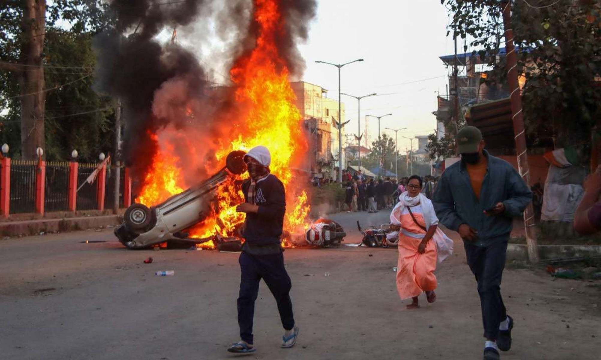  People run past burning vehicles of India's Bharatiya Janata Party (BJP) MLA during a protest to condemn the alleged killing of women and children in Imphal, capital of India's violence-hit northeastern state of Manipur on November 16, 2024. An Indian state riven by months of ethnic tensions imposed an internet shutdown and curfew November 16 after angry protests over the recovery of six bodies of people believed to have been kidnapped by insurgents. (Photo by AFP)
     -  (crédito:  AFP)