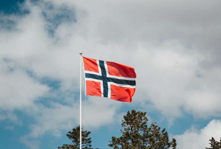 A bandeira dac Noruega tem o fundo vermelho e a cruz azul marinho com envoltório branco