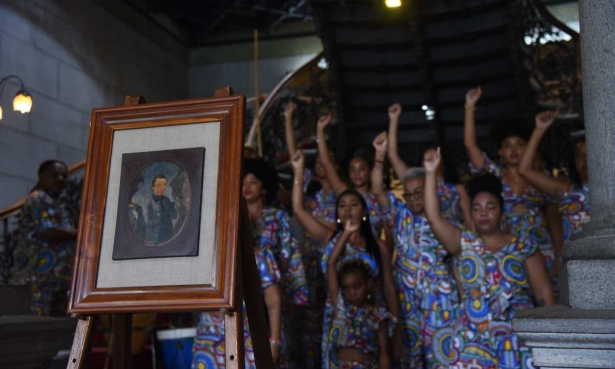 20/11/2024. Brasil. Belo Horizonte-MG. O Governo de Minas, por meio da Secretaria de Estado de Cultura e Turismo e da Fundacao Clovis Salgado, realiza a entronizacao do Mestre Aleijadinho, patrono da arte do Brasil, na Sala dos Grandes de Minas, no Palacio da Liberdade, no Dia da Consciencia Negra. Esta e a primeira vez que um artista negro sera representado neste espaco nobre que homenageia outros grandes nomes do estado, como Santos Dumont, Juscelino Kubitschek, Tancredo Neves e Tiradentes. Na foto, quadro do Mestre Aleijadinho com o Coral Vozes de Campanha do Quilombo de Justinopolis, em Ribeirao das Neves, ao fundo. -  (crédito: Gladyston Rodrigues/EM/D.A. Press)
