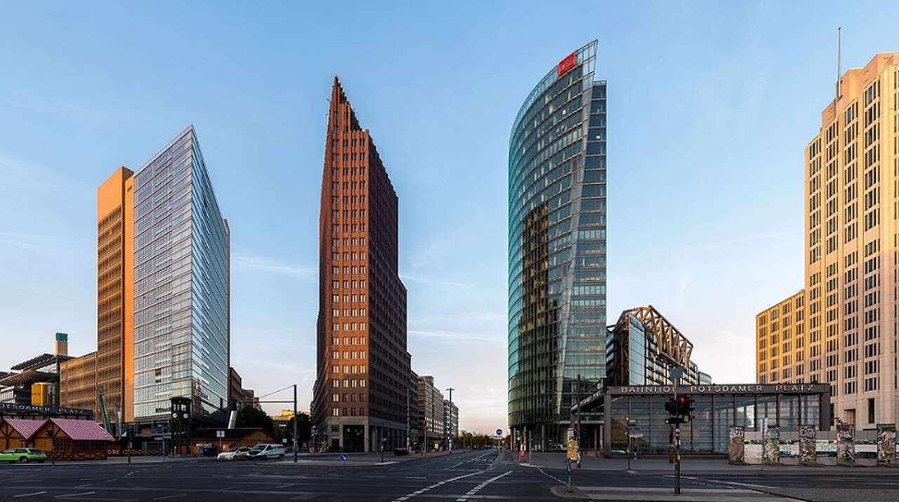 Potsdamer Platz - Descrição: Um dos centros mais vibrantes de Berlim, a Potsdamer Platz foi reconstruída na década de 1990 após a queda do Muro de Berlim e é hoje um símbolo da nova Berlim, com arranha-céus modernos e espaços culturais - Localização: Mitte - Referências Históricas: Antes da Segunda Guerra Mundial, era um dos pontos mais movimentados da Europa; depois, ficou destruída e vazia durante a Guerra Fria