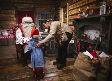 Menina e a mãe dela são recebidas pelo Papai Noel no escritório do Parque do Papai Noel, na Finlândia -  (crédito: Jonathan NACKSTRAND / AFP)