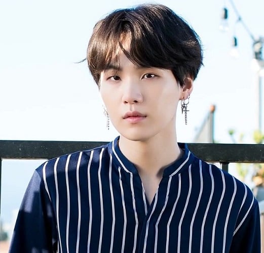 Suga, cujo nome verdadeiro é Min Yoongi, é um rapper, compositor e produtor do grupo BTS, o mais famoso de K-Pop no mundo. Ele é conhecido por suas letras introspectivas e por abordar temas como saúde mental e autoaceitação. Sua influência se estende além da música, impactando jovens em todo o mundo.