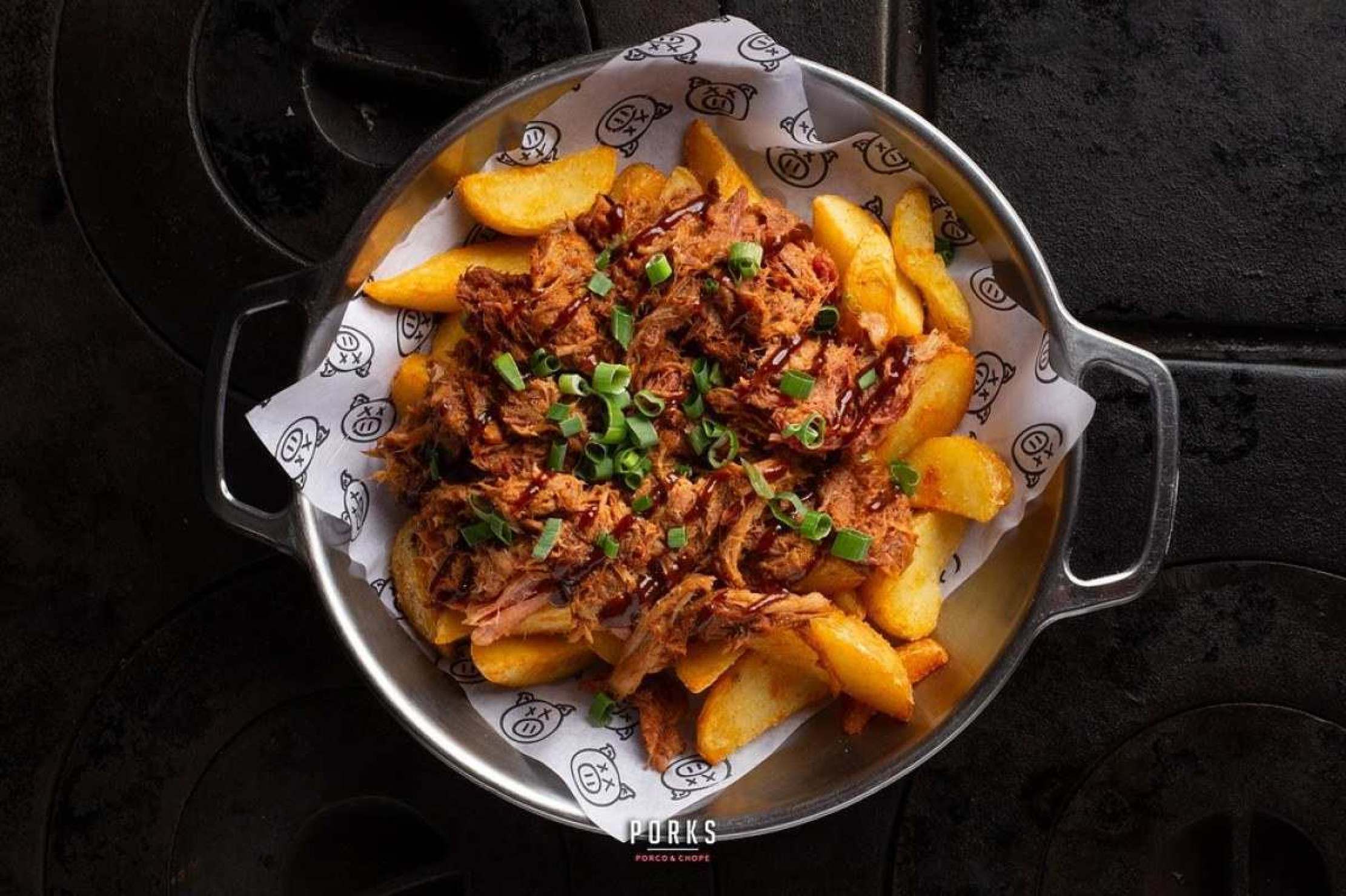 A Batata tropeira do Porks é feita com batata rustica coberta por pernil desfiado e molho barbecue