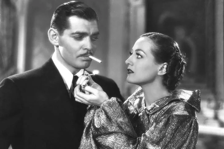 Aqui é o oposto. A mulher é que acende o cigarro do homem. Clark Gable, galã de sua geração, dá aquela olhada em Joan Crawford com o cigarro a postos. 