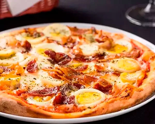 Americana - Entre as diferentes versões que existem, a pizza americana geralmente leva tomate, muçarela, ovos fatiados e bacon. Sugerida por Dom Carmino.