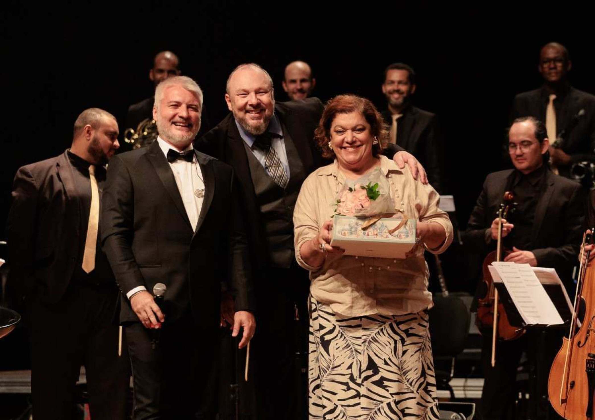 Fred Mayrink, maestro Leonardo Cunha e Sandra Campos sorriem, no palco do Cine Theatro Brasil, em BH