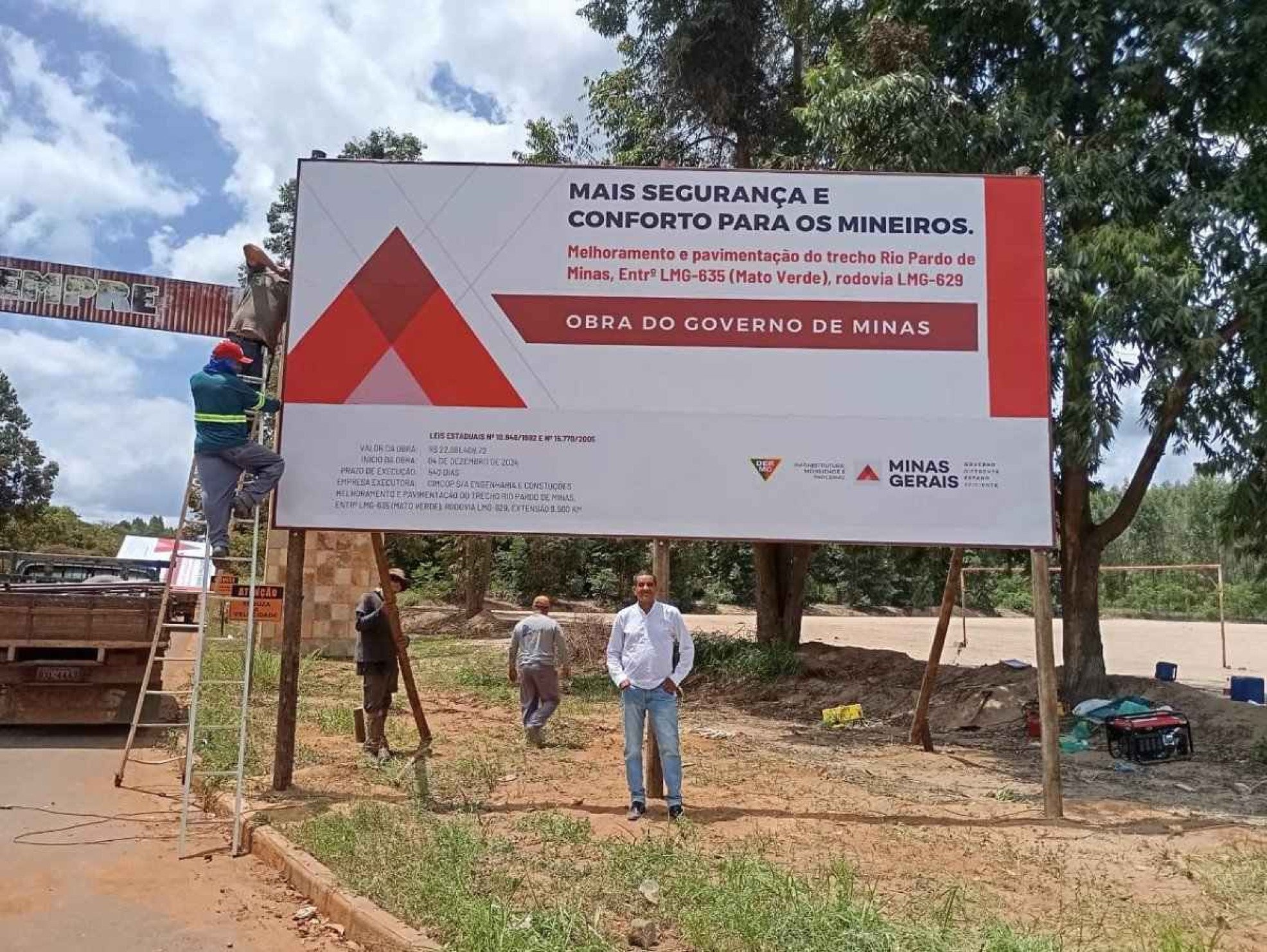 Wandenilson Ribeiro, o Nilson, morador de Rio Pardo de Minas com a placa que anuncia as obras de pavimentação da LMG-629, que liga a cidade à vizinha Mato Verde