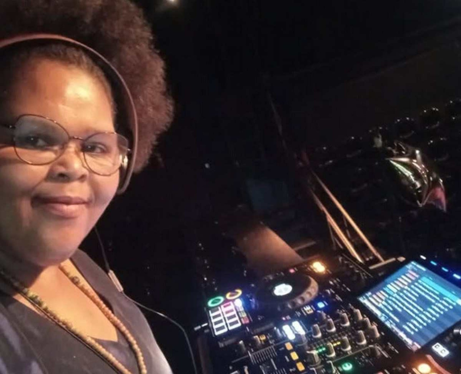 Black Josie, DJ atuante na cena musical de BH, está de lado em frente às picapes e olha para a câmera. Ela vai se apresentar no ano novo em BH