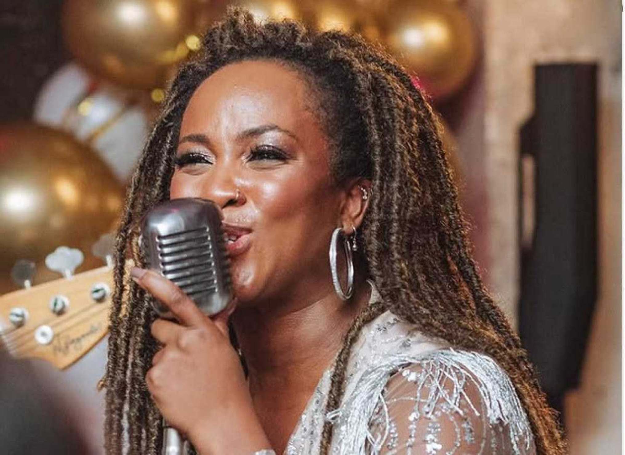 Nêga Kelly canta e segura o microfone. Cantora é atração do reveillon de 2025 em BH