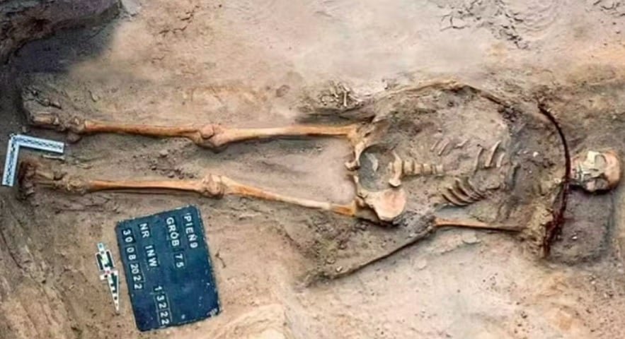 A jovem de 18 anos estava sepultada com uma foice sobre o pescoço e um cadeado no dedo do pé, medidas usadas para impedir que ela “retornasse dos mortos” – uma prática de proteção contra supostos “vampiros”.  O corpo da jovem tinha deformidade física e a comunidade pode ter considerado 