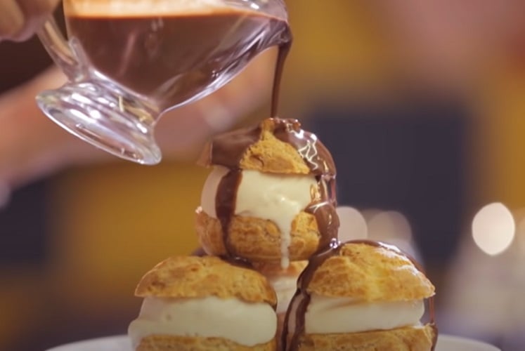 Profiteroles - Pequenos bolinhos recheados com creme de confeiteiro e cobertos com chocolate derretido, uma sobremesa clássica da culinária francesa