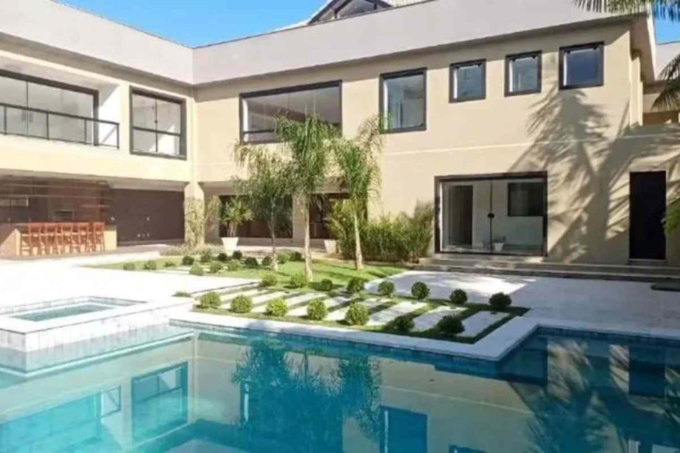 A área de lazer da mansão com piscina, um pequeno jardim e uma área gourmet 