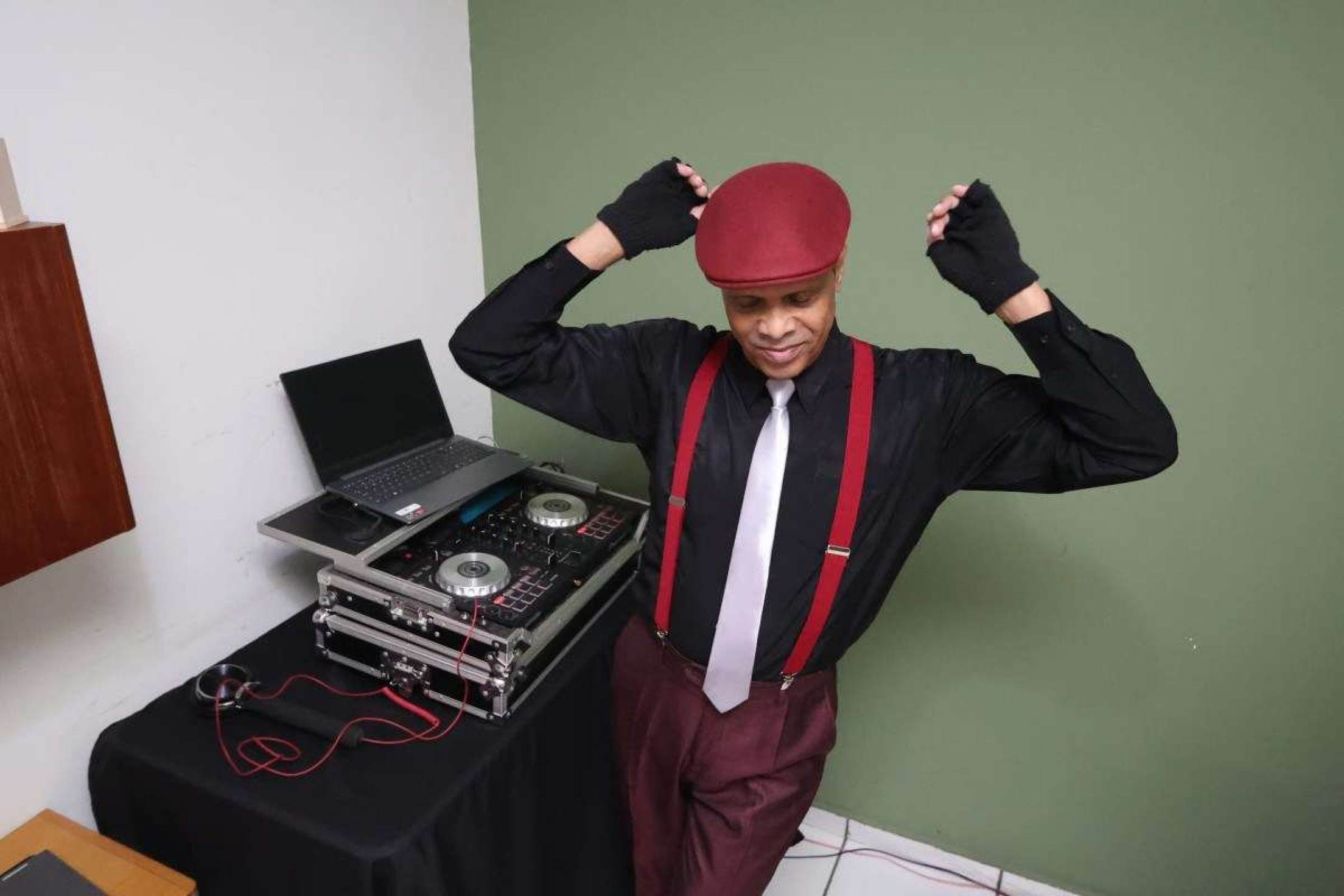 Ricardo Malta ao lado do equipamento que usa para tocar como DJ fazendo passos de dança