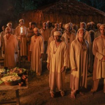  Negros escravizados estão reunidos diante de mesa com comida na cena do filme Malês, de Antonio Pitanga, que será exibido na Mostra de Tiradentes 