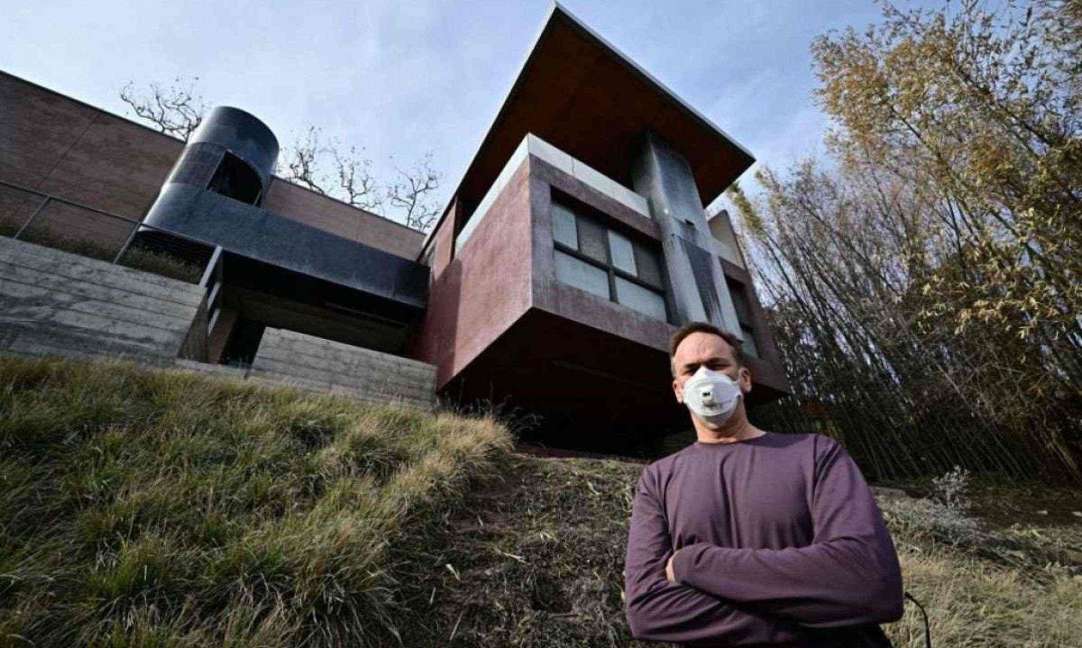 Arquiteto americano Michael Kovac e a casa dele, que sobreviveu ao incêndio em Los Angeles devido às características resistentes ao fogo usadas na construção
       -  (crédito: Frederic J. Brown / AFP)