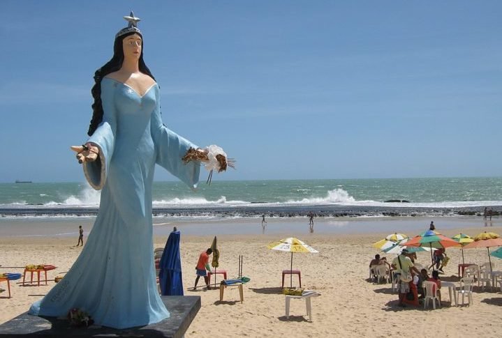 A imagem de Iemanjá varia conforme as tradições locais, mas geralmente é representada como uma mulher majestosa, muitas vezes vestida em tons de azul e branco, segurando símbolos como conchas e peixes. 