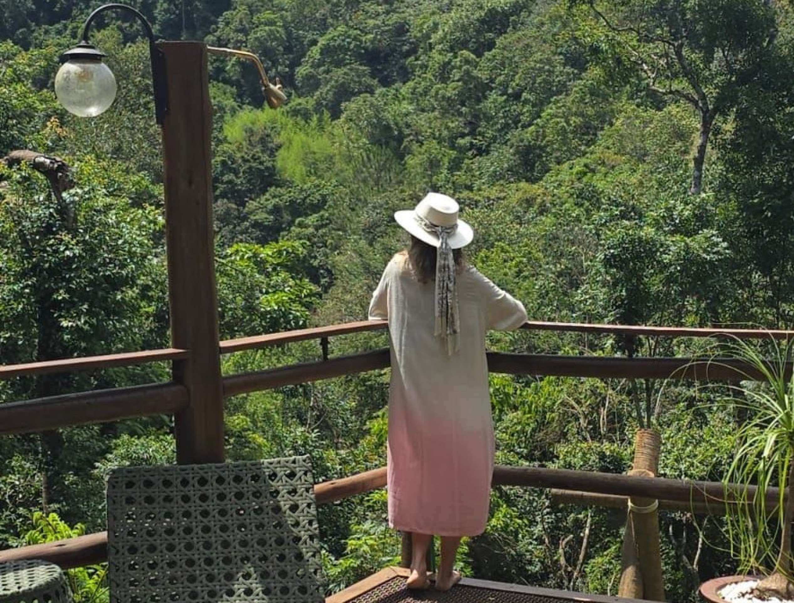 Mulher está de costas, diante de bela paisagem de montanha vista da Casa Verde, em Macacos, Minas Gerais