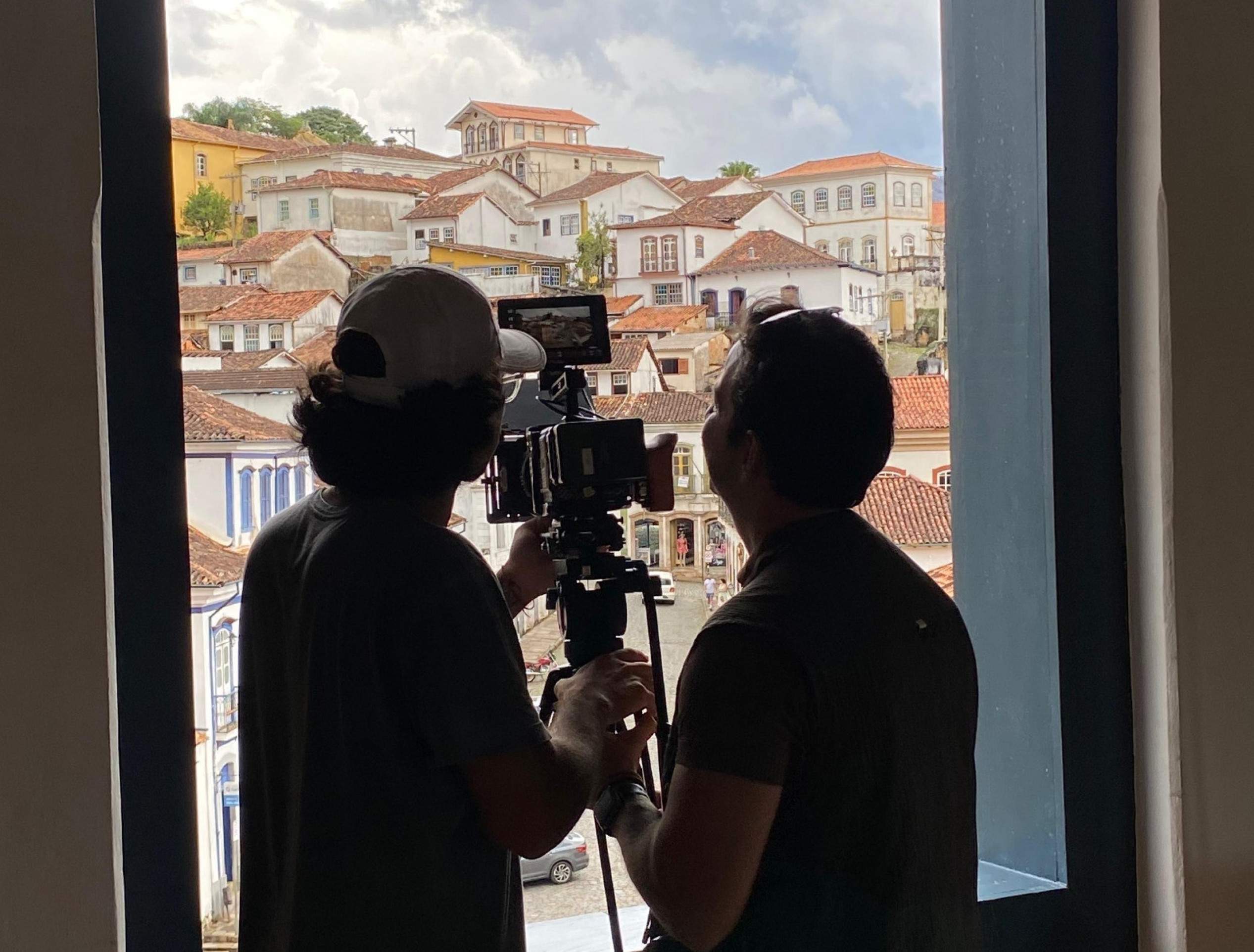 Casario barroco foi filmado para ser exibido no espetáculo 'Aquele abraço', no Roxy Dinner Show Dois rapazes estão de costas, filmando de uma janela o casario barroco de cidade histórica mineira