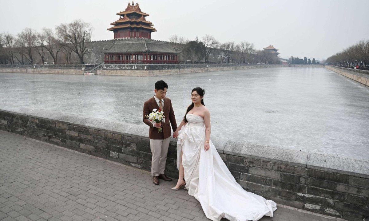 Casal posa para fotografias de casamento fora da Cidade Proibida, em Pequim; China registrou ano passado declínio de um quinto nos casamentos, o mais recente sinal de desafios demográficos persistentes -  (crédito: GREG BAKER / AFP)