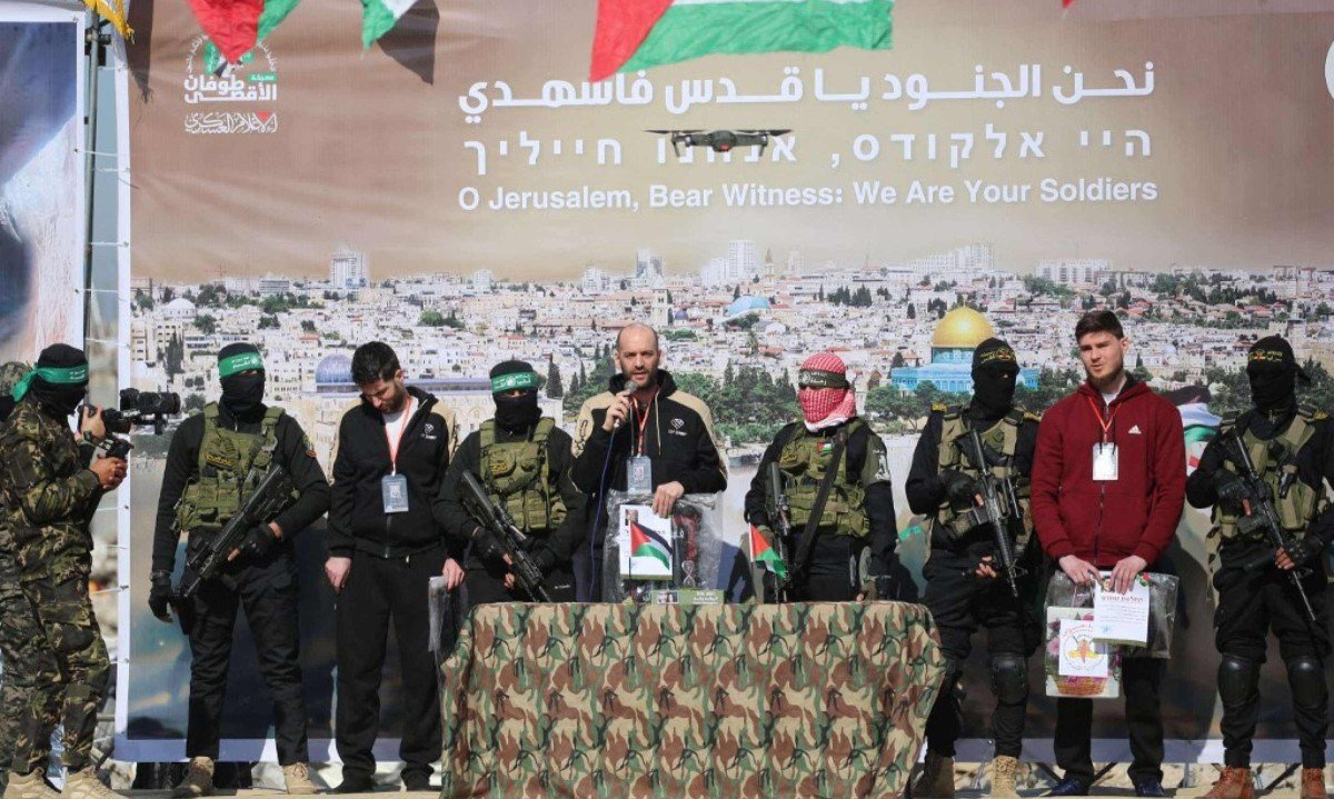  Reféns da esquerda para a direita: o israelense-americano Sagui Dekel-Chen, o refém israelense-argentino Yair Horn e o israelense-russo Sasha Trupanov estão no palco ao lado de sequestradores do Hamas -  (crédito: Eyad BABA / AFP)