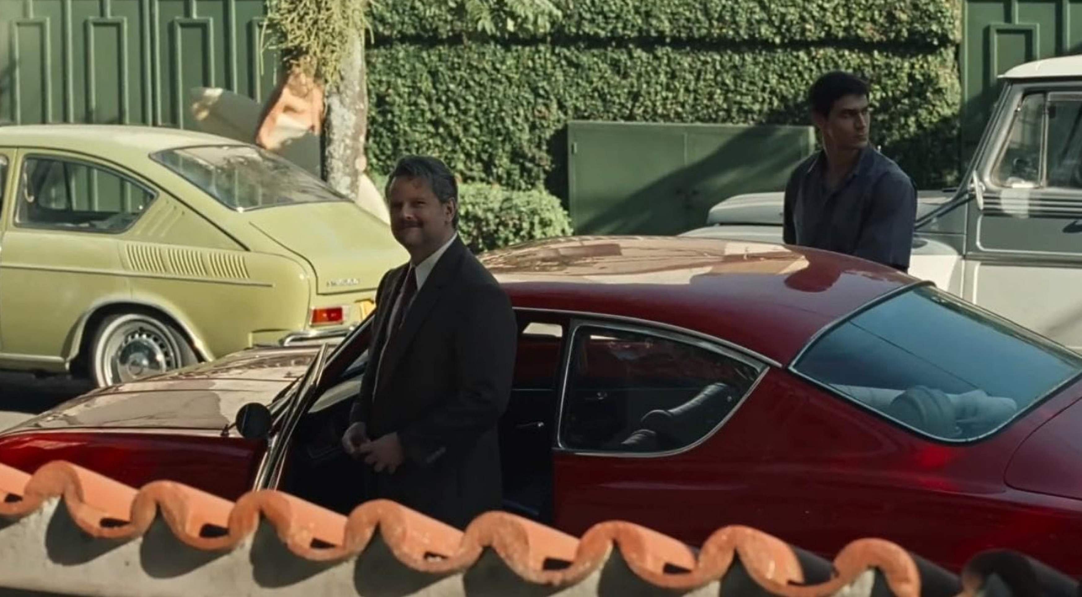 Em cena do filme Ainda estou aqui, Selton Mello está na rua em frente a um carro e olha para dentro de casa
