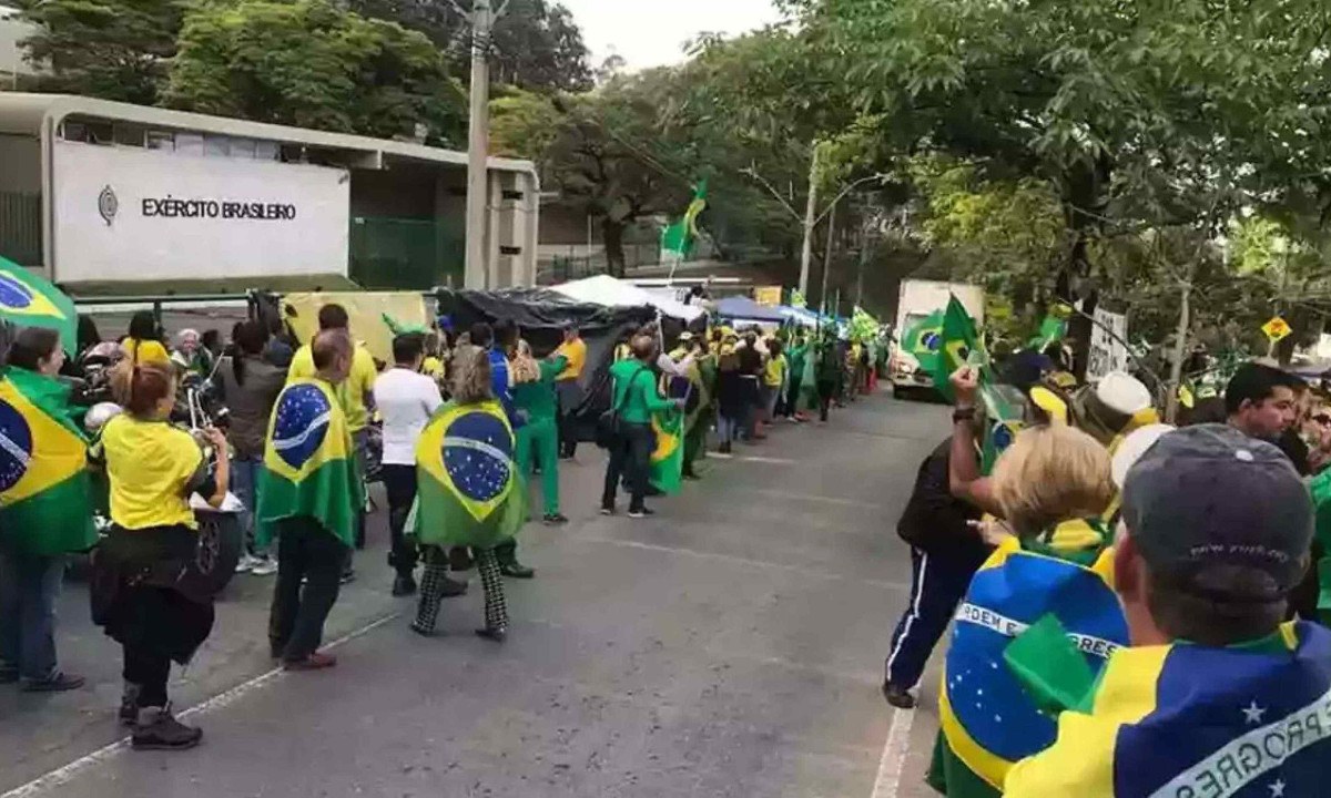 Bolsonaristas com bandeiras do Brasil às costas fazem 'corredor' na pista da Av. Raja Gabaglia, em BH, em novembro de 2022 -  (crédito: Ramon Lisboa/EM/DA Press)