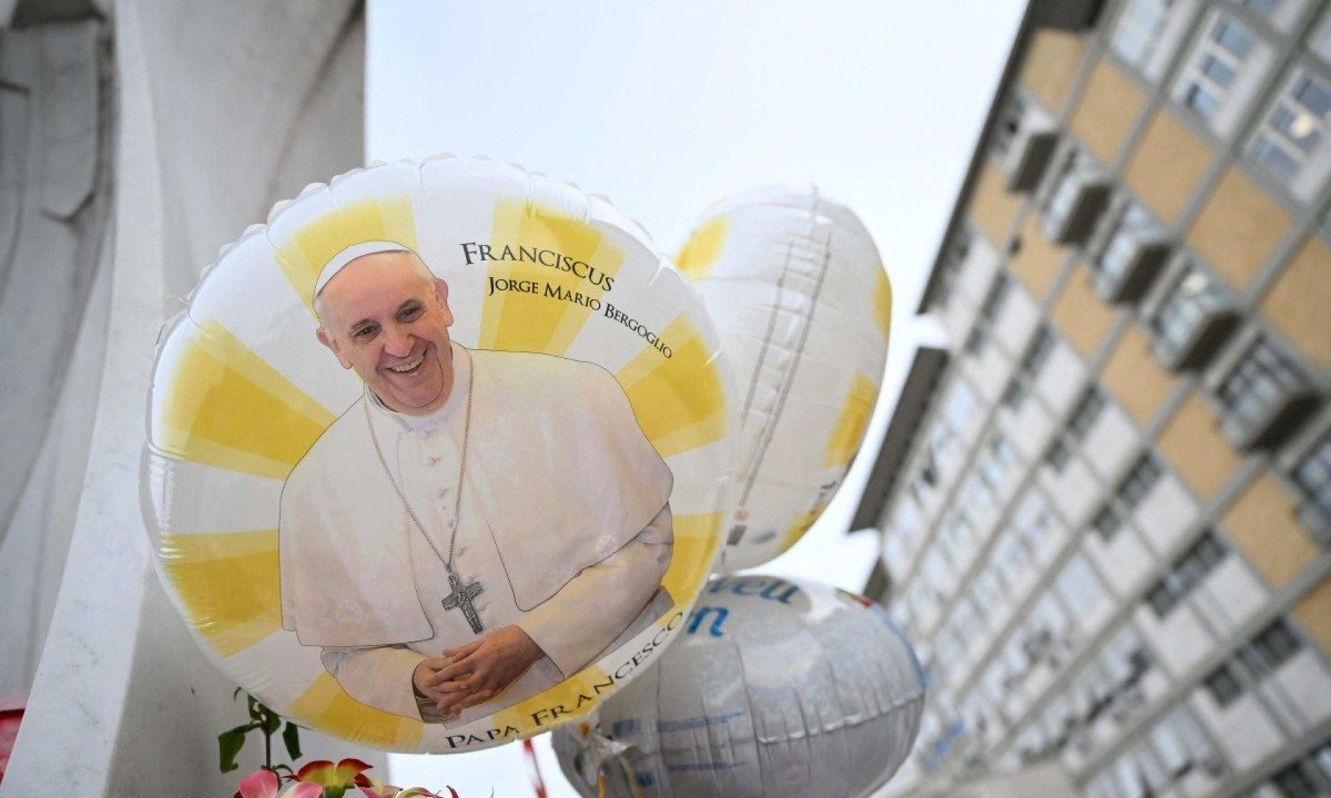  Balões com a imagem do Papa colocados na estátua de João Paulo II fora do hospital Gemelli, onde Francisco está internado -  (crédito: ALBERTO PIZZOLI/AFP)