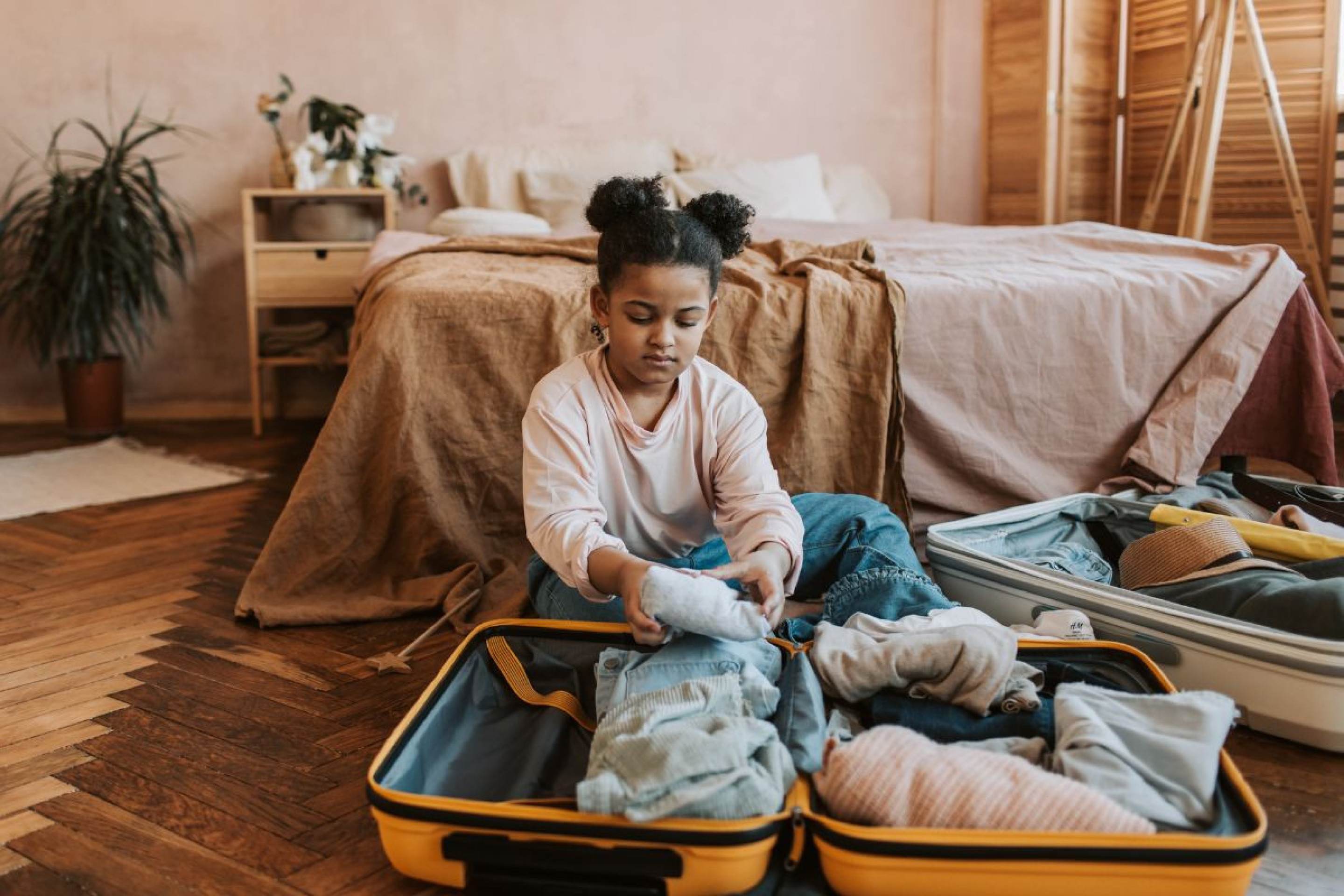 Viajar com menores de idade exige atenção especial, pois há regras específicas para garantir a segurança das crianças e adolescentes Criança arrumando a mala de viagem