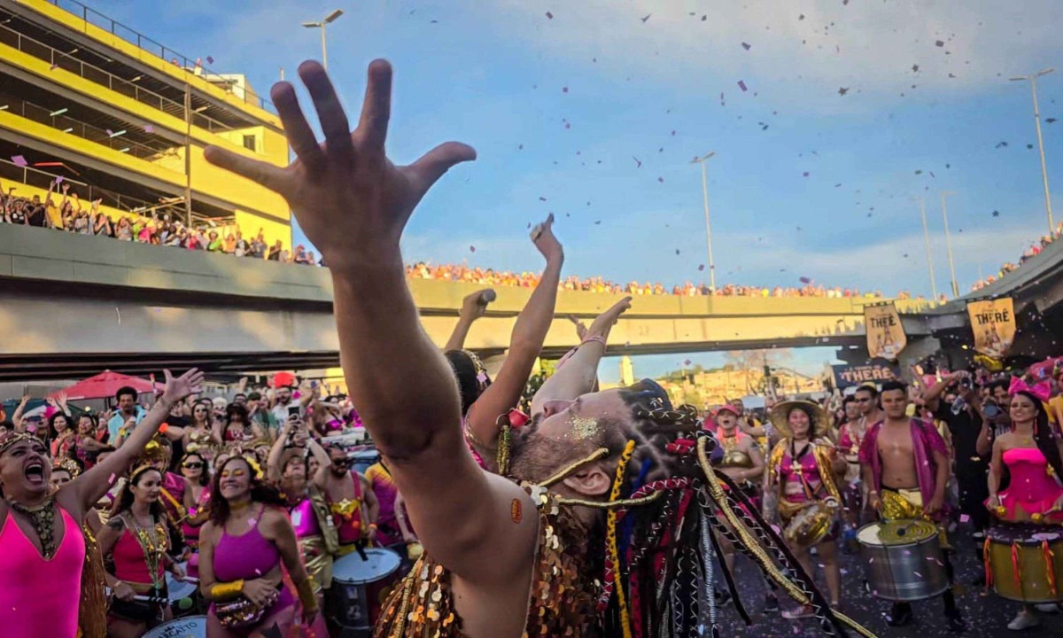 Foliões erguem os braços à frente da bateria celebrando a abertura do Carnaval de BH com o Então, Brilha